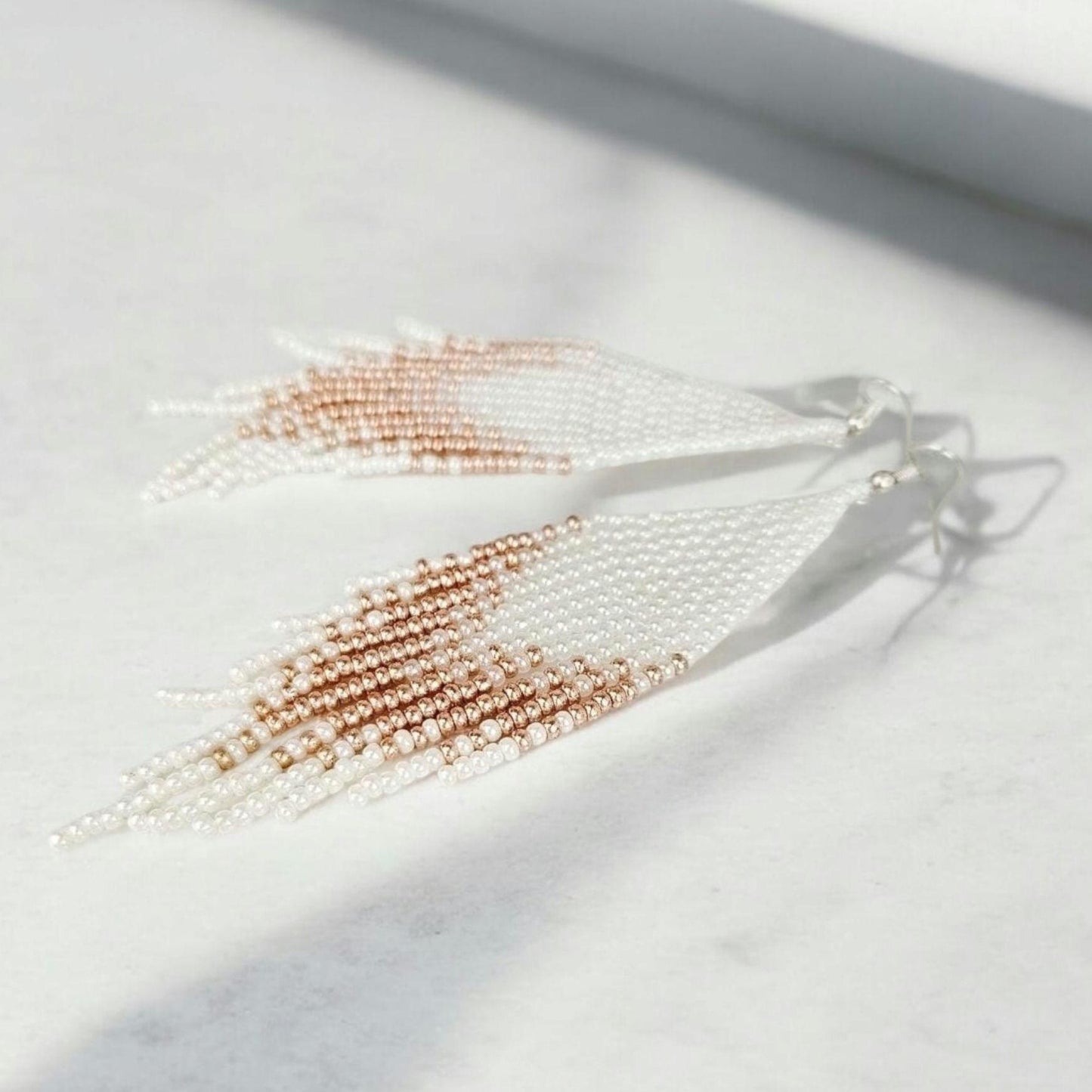 Pearl and rose gold tassel earring on a light background