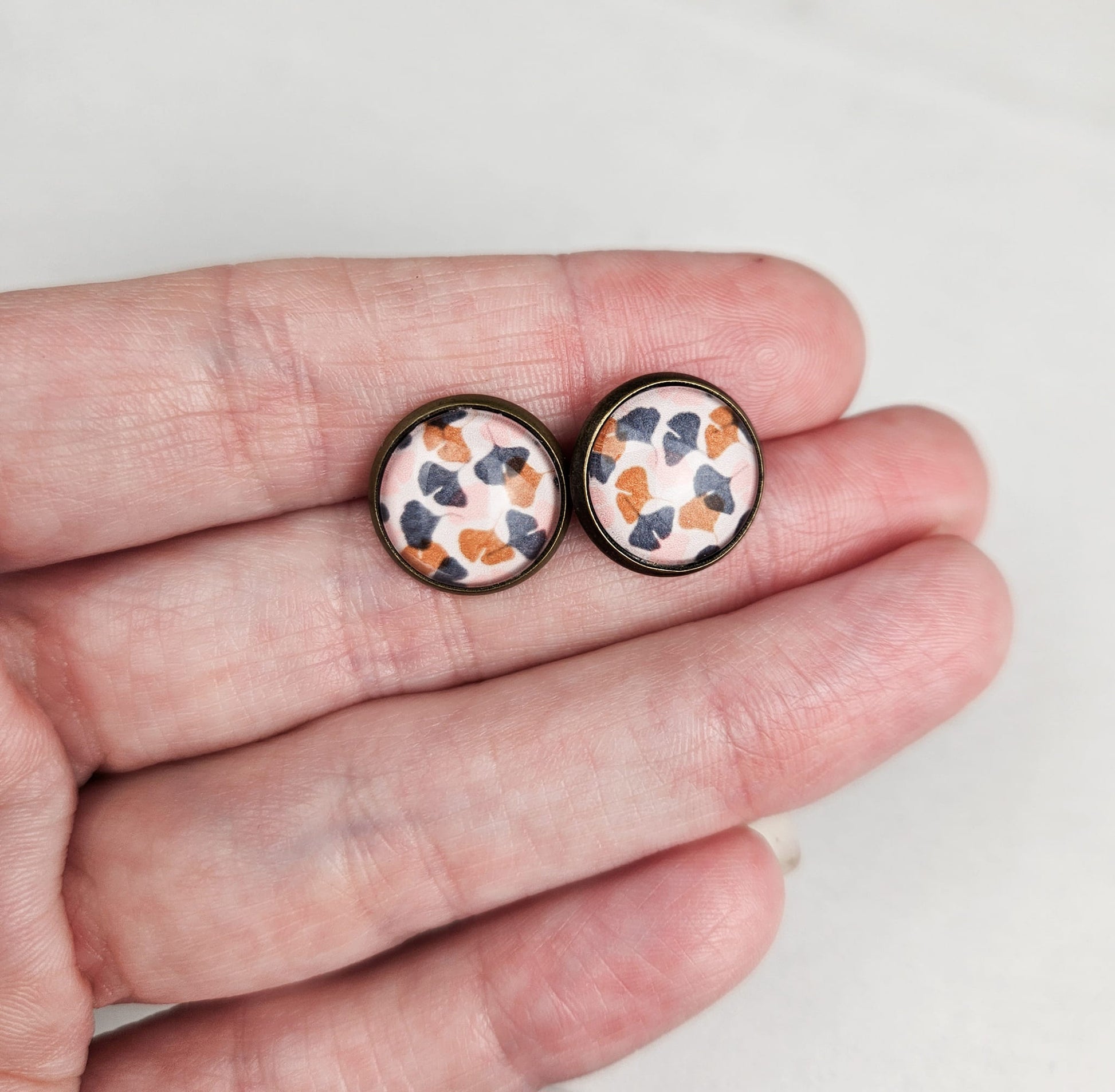 monstera and ginkgo leaf bronze stud glass earrings size comparison to hand