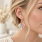 Blonde woman wearing blush pink, ivory and grey marbled polymer clay fan earrings with gold-tone hooks.