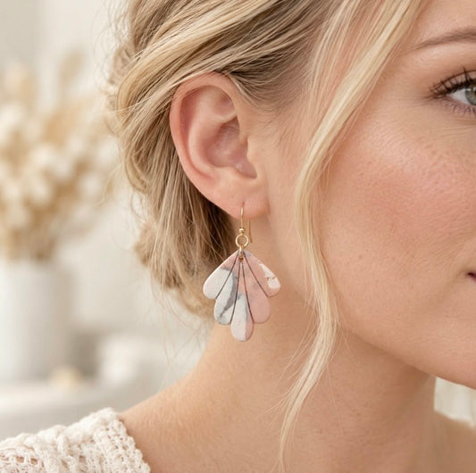 Blonde woman wearing blush pink, ivory and grey marbled polymer clay fan earrings with gold-tone hooks.