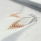 Pearl and rose gold tassel earring on a light background
