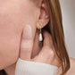 Close-up of a person wearing a pearl earring with a neutral background