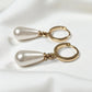 Pair of gold hoop earrings with pearl drops on a white background