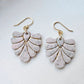 Blush pink and ivory speckled polymer clay fan earrings with gold accents on a white background.