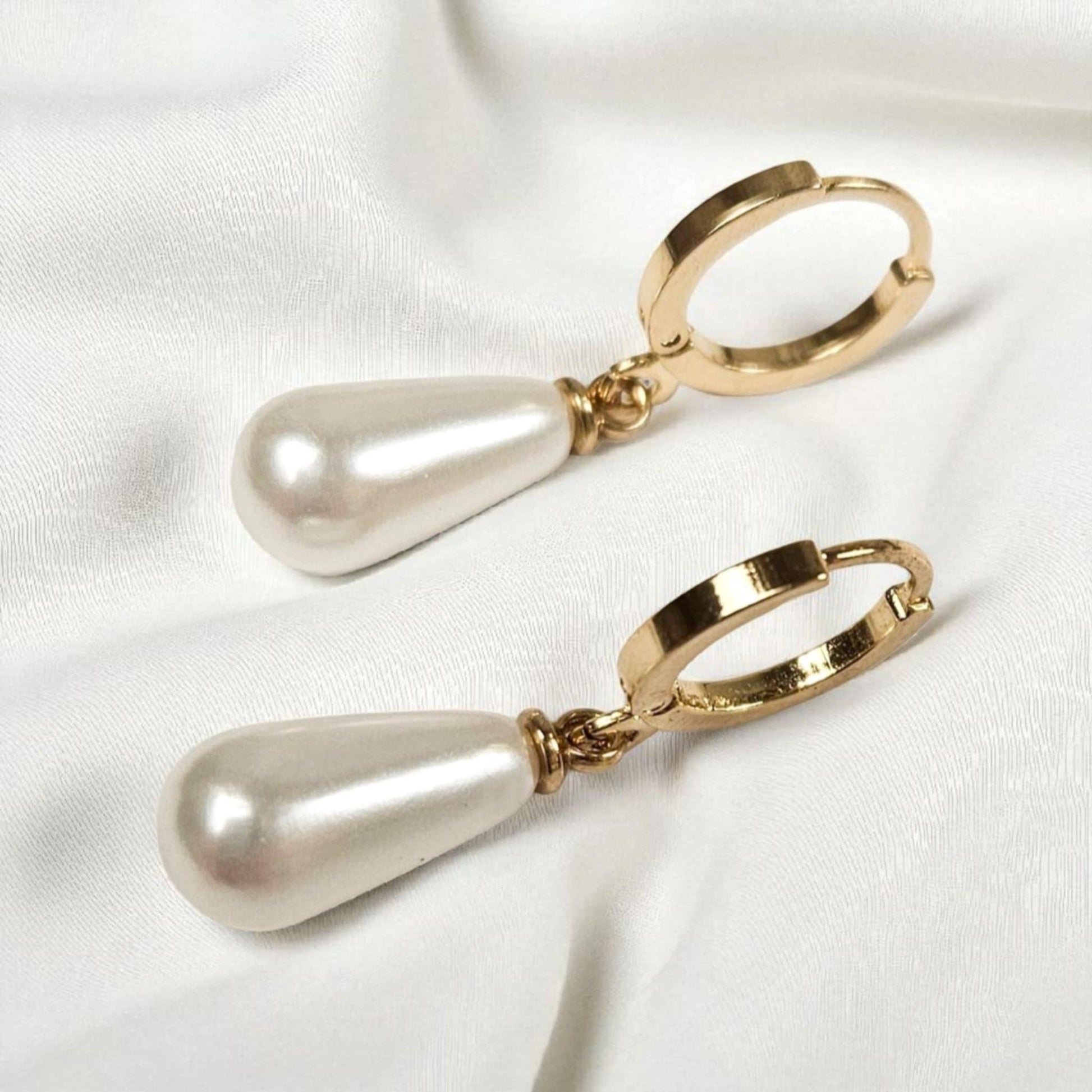 Gold hoop earrings with pearl drops on a white background