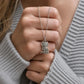 Silver owl pendant necklace held by a hand against a gray sweater background