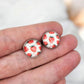 Silver strawberry stud earrings featuring hypoallergenic stainless steel posts and a cute strawberry glass dome design. Lightweight for comfortable all-day wear. Hand size comparison.