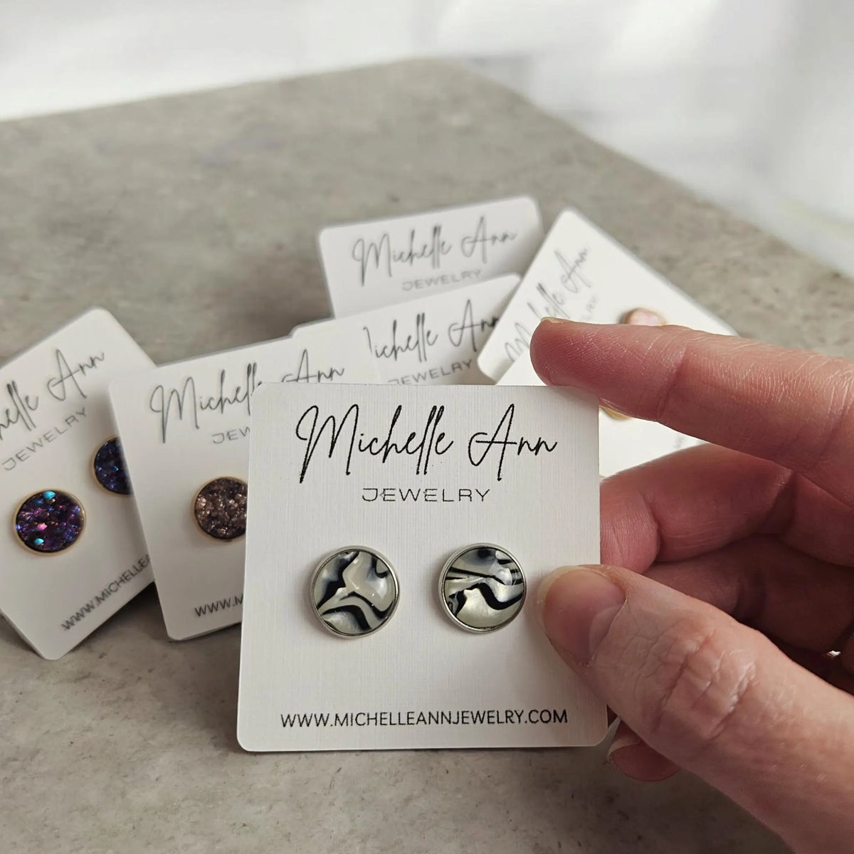 A pair of zebra print stud earrings featuring 12mm resin domes with a bold black and white pattern, set into a astainless steel post setting.