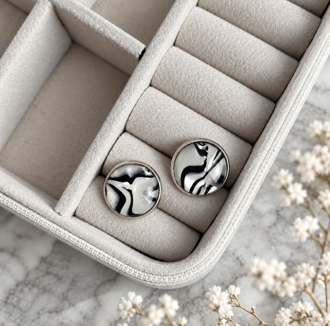 Black and white zebra print round stud earrings with resin domes and stainless steel settings, displayed inside a soft beige jewellery box.